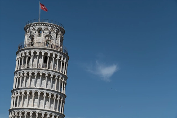 The Leaning Tower of Pisa with open sky and a flag.